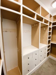 an empty walk - in closet with white drawers and shelves on each side, painted tan