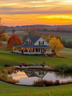 a house with a pond in front of it and trees around the lake at sunset