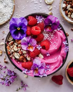 a bowl filled with raspberries, almonds and flowers