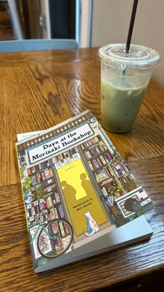 a book sitting on top of a wooden table next to a drink