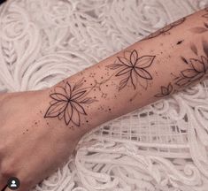 a woman's arm with flowers on it and dots in the middle, while she is wearing a white lace dress