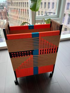 a planter made out of cardboard sitting on top of a hard wood floor next to a window