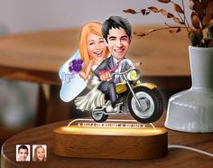 a wedding cake topper with a bride and groom on a motorbike next to a vase