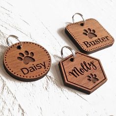 three wooden tags with the words daisy and paw prints on them