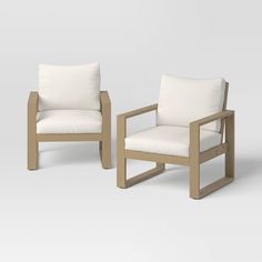 two wooden chairs with white cushions sitting next to each other