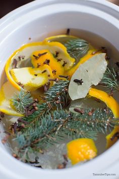 a white crock pot filled with lemon slices and herbs