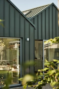 a green building with glass doors and windows on the outside, looking out onto an outdoor patio area