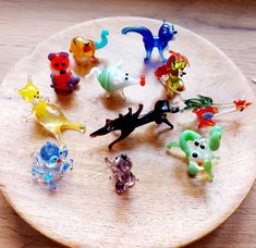 there are many small toy animals on the wooden plate, all in different colors and sizes