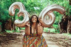 a woman in a colorful dress is holding two large balloons that spell out the number 30