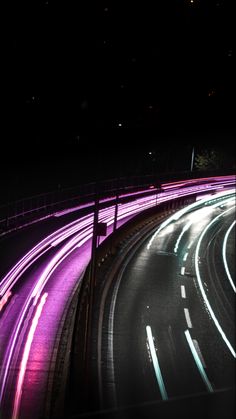 an image of a city street at night with light streaks on the road and buildings in the background