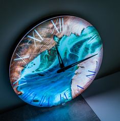 a clock that is on the side of a wall with water and rocks painted on it