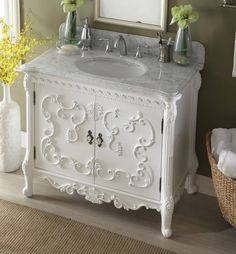 a white bathroom sink sitting under a mirror next to a basket filled with yellow flowers