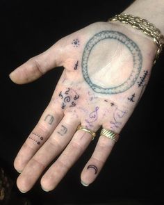 a person's hand with tattoos on it and writing all over the palm area