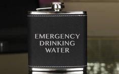 a flask with the words emergency drinking water written on it is sitting on a table