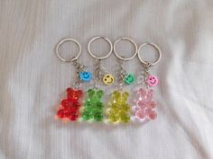 four gummy bears with smiley faces are on a white sheet and one is in the shape of a keychain