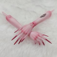 a fake hand with pink nail polish on it's arms and hands, resting on a white fur surface