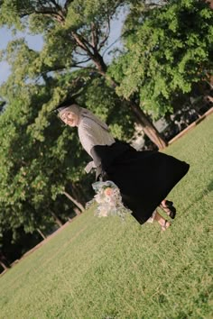 a woman in a skirt and top is walking on the grass with a plastic bag