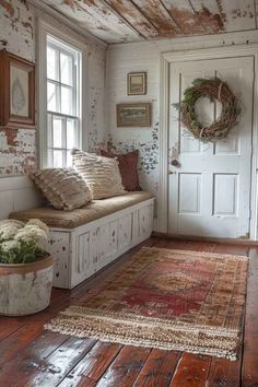 a room with a bench, rug and wreath on the wall next to a door