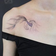 a woman's shoulder with a tattoo on the back of her neck and an image of a fish coming out of it