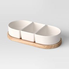 three white bowls sitting on top of a wooden tray