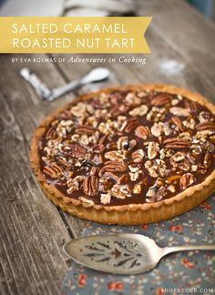 a chocolate pecan pie sitting on top of a wooden table next to a spoon