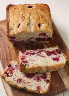 sliced loaf of fresh fruit bread sitting on top of a wooden cutting board