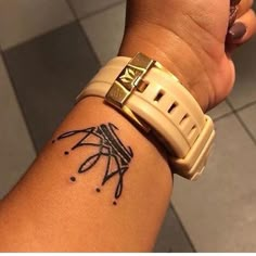 a person with a tattoo on their arm holding onto a wrist watch and looking at the camera