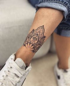 a woman's foot with a tattoo on her left leg and a white sneaker