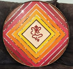 a decorative plate sitting on top of a couch next to a black pillow and wall