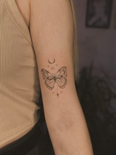 a woman with a butterfly tattoo on her arm and the moon in the sky behind her