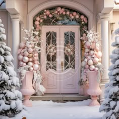 a pink door decorated with christmas decorations and ornaments in front of snow - covered trees