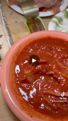 a pink bowl filled with sauce on top of a wooden table