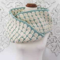 a white and blue crocheted cowl on a mannequin headpiece