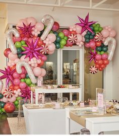 balloons and decorations are displayed in front of a store window for the holiday season, as well as other festive items