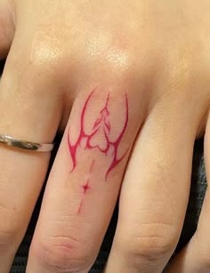 a woman's hand with a red ink tattoo on her left thumb and ring finger