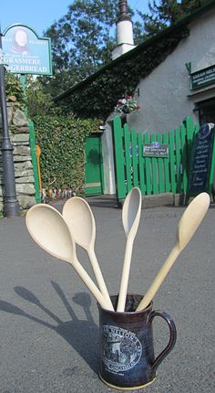 spoons and spatulas are in a coffee cup on the pavement outside a restaurant