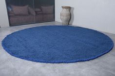 a blue rug is in the middle of a room with a vase on the floor