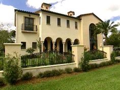 a large white house sitting on top of a lush green field next to a fence