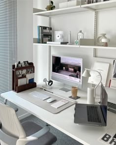 a desk with a laptop, monitor and keyboard on it in front of a bookshelf