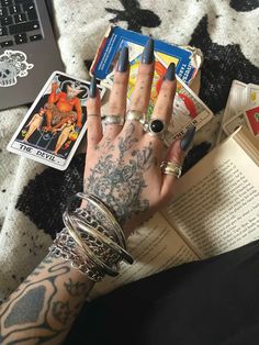 a person with tattoos on their arms and holding an open book