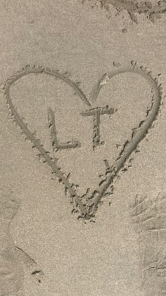 a heart drawn in the sand with a cross on it