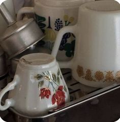 several cups and saucers are sitting on the stove top, with one teapot in the middle