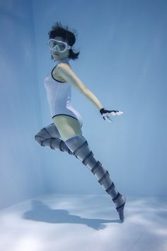 a woman is diving in the water with goggles on her head and legs,