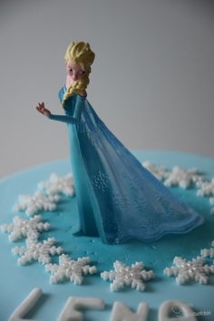 a frozen princess cake with snow flakes on the bottom and frosting around it