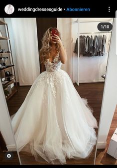 a woman taking a selfie while wearing a wedding dress in front of a mirror