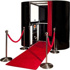 a red carpet is in front of an old fashioned phone booth with barriers and ropes