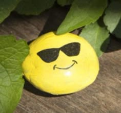 a yellow smiley face with sunglasses on it's head and green leaves around it