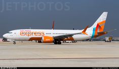 an orange and white jet airliner sitting on the tarmac at an air port