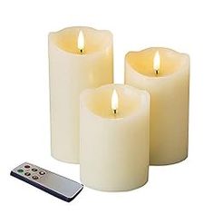 three lit candles with remote control on white background