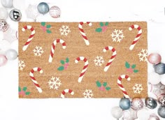 a door mat with candy canes and snowflakes on it next to ornaments